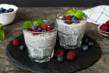 Healthy breakfast or morning with chia seeds vanilla pudding raspberry and blueberry berries on table background, vegetarian food, diet and health concept. Chia pudding with raspberry and blueberry