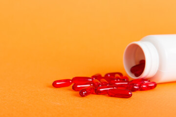 Red pills spilled around a pill bottle. Medicines and prescription pills flat lay background. Red...