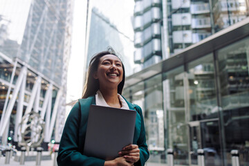 Smiling businesswoman holding a folder in a modern city financial district