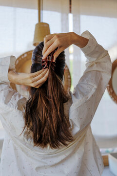 Woman styling hair with a claw clip in the bathroom during morning routine
