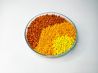 yellow orange color gradation masterbatch granules, in laboratory dish isolated on white...