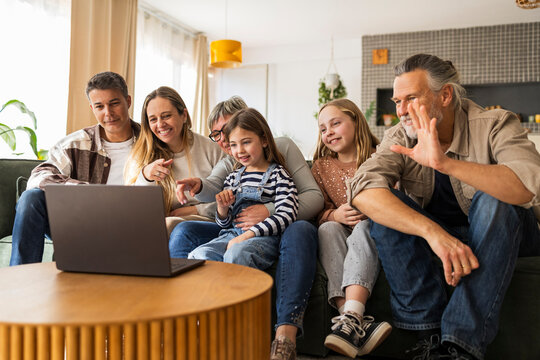 Three-generation family sitting on couch having a video call