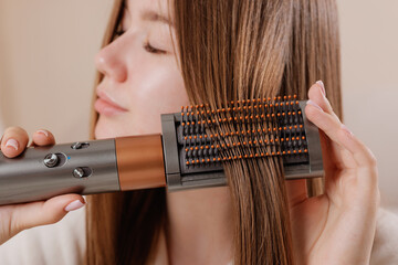 Hair straightening with round hot air brush for sleek styling at home.