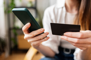 Woman using smartphone and credit card for online shopping at home