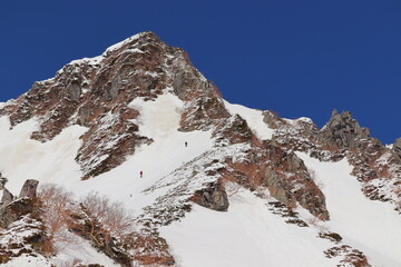 冬の雪山を登る二人 頂上間近の挑戦と努力の瞬間