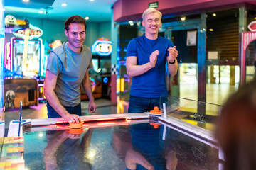 Friends playing air hockey in entertainment center