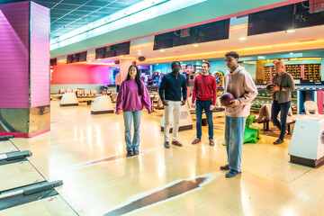 Young multiethnic friends enjoying bowling together at a colorful alley