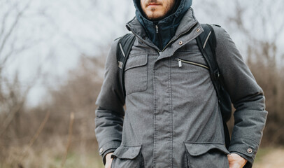 A winter-clad person is seen outdoors in a natural setting, wearing a backpack. The image captures a raw and authentic moment, evoking themes of travel, survival, and exploration in the wilderness. © qunica.com