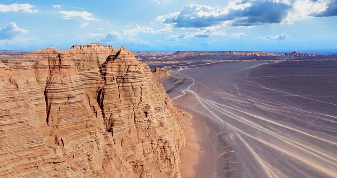 Aerial shot of spectacular yardang landforms and vast desert with vehicle tracks in Xinjiang, China.