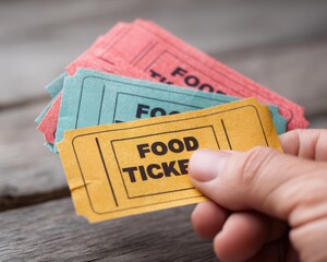 A hand holds colorful food tickets, suggesting entry to a food-related event or festival.
