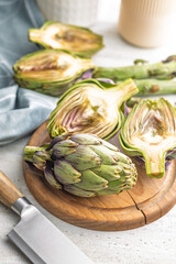 Ripe artichokes plant on wooden cutting board.