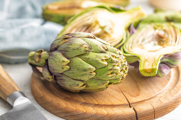 Obraz premium Ripe artichokes plant on wooden cutting board.