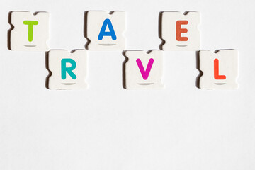 TRAVEL – Word assembled from colorful puzzle letters on white background