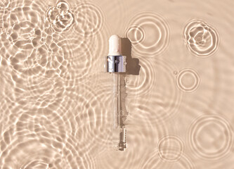 pipette serum in water on beige background ripples water drops natural sunlight