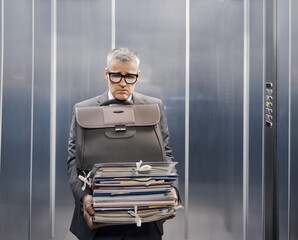 Frustrated office worker carrying a lot of paperwork