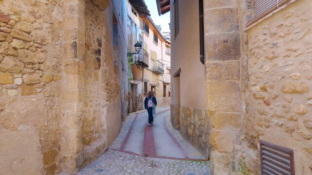 Tourist woman strolling through the streets with stone arches in the medieval village of Beceite, Teruel, Spain.