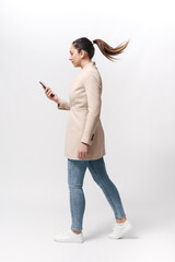 Young woman walking and checking her smartphone