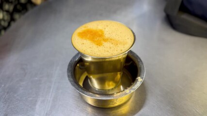 Close-up of South Indian filter coffee with rich froth in a traditional brass tumbler