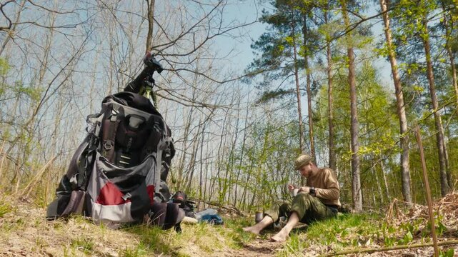 Camper Enjoying Tea in a Forest with Backpack and Spring Sunlight