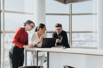 Business employees engage in a collaborative discussion around a laptop in a bright, modern office...