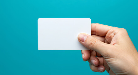 Fototapeta premium close up of a Hand holding blank credit card or business card on turquoise background