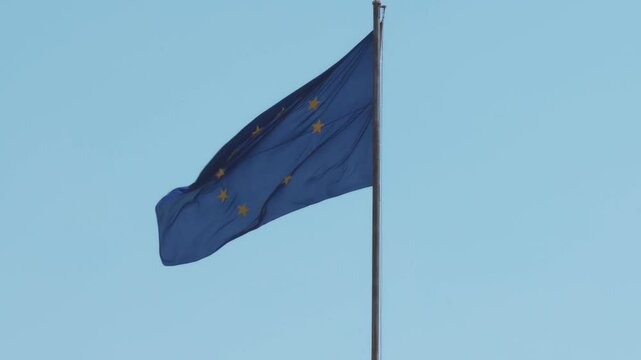 The bright blue flag with yellow stars flutters in the wind against a stunning sky backdrop