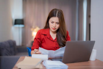 Young professional woman feeling stressed and frustrated while working on a laptop and reviewing...