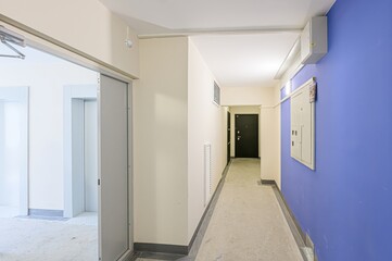 interior apartment public place, well-lit hallway with elevators and doors. The walls are painted in cream and blue.