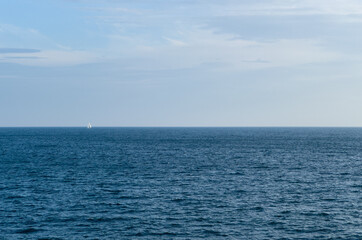 Obraz premium Blue sea and sky and single sailboat 