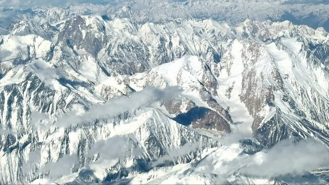 Snow-covered Pamir mountains aerial view under blue sky and white clouds