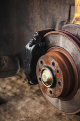 Rusty rear wheel hub of a car with a brake disc in a tire shop. A car without a wheel during...
