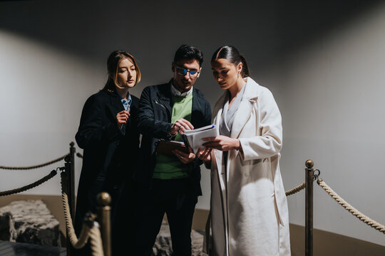 A group of three people engage in discussion while examining museum exhibits in a sophisticated setting, reflecting education, collaboration, and the enriching experience of exploring cultural and