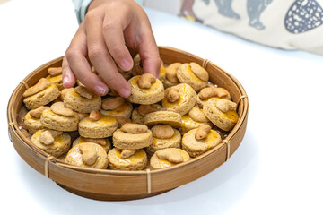 Delicious Round Cashew Cookies Topped with Cashew Nuts, Arranged  in a Traditional Woven Basket, isolated on  White, Perfect for Eid Al-Fitr Celebrations, Selective Focus