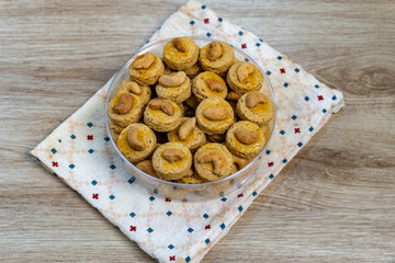 Delicious Round Cashew Cookies Topped with Cashew Nuts, Arranged in a Clear Bowl on a White and Blue Patterned Napkin, Perfect for Eid Al-Fitr Celebrations