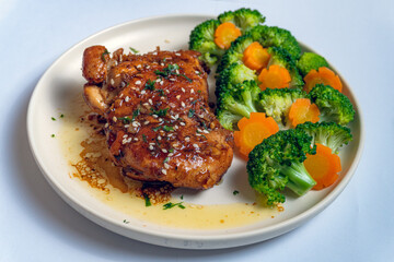 Honey Lime Garlic Chicken Thigh with Bright Broccoli Florets and Elegant Carrot Cuts, Sprinkled with Sesame Seeds and Fresh Herbs, Served on a White Plate for a Healthy and Delicious Meal