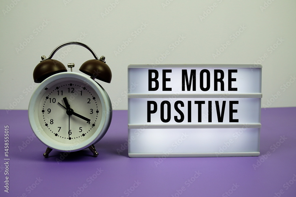 Poster be more positive text on led lightbox with alarm clock on purple background