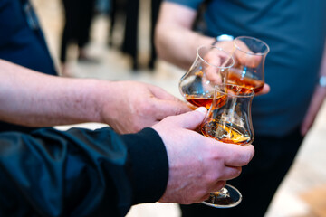 Close-up of two hands holding glasses of cognac or brandy