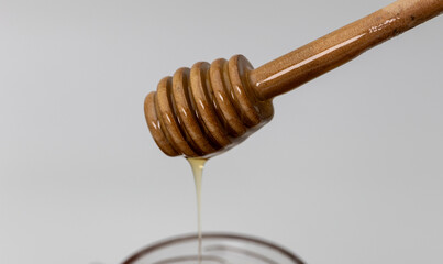 Close up shot of honey dripping from a honey dipper