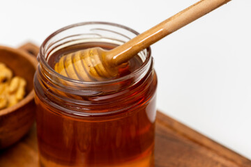 Close up shot of honey dipper immersed in a jar of honey