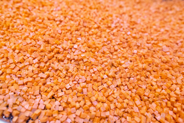 Bright diced carrot pieces fall from the shredder&rsquo;s collector onto a moving mesh conveyor belt before entering the shock-freezing chamber.