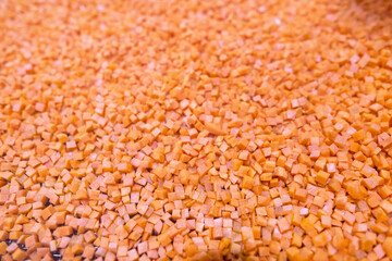 Bright diced carrot pieces fall from the shredder’s collector onto a moving mesh conveyor belt before entering the shock-freezing chamber.