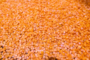 Bright diced carrot pieces fall from the shredder’s collector onto a moving mesh conveyor belt before entering the shock-freezing chamber.