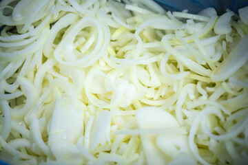 Close-up of shock-frozen onion rings and half-rings with a thin ice coating. Are prepared for retail packaging to ensure extended shelf life in supermarkets and maintain perishable harvest quality.