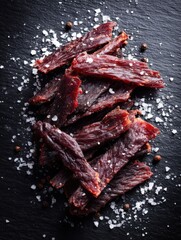 Sliced Dried Meat on Black Slate with Sea Salt and Peppercorns