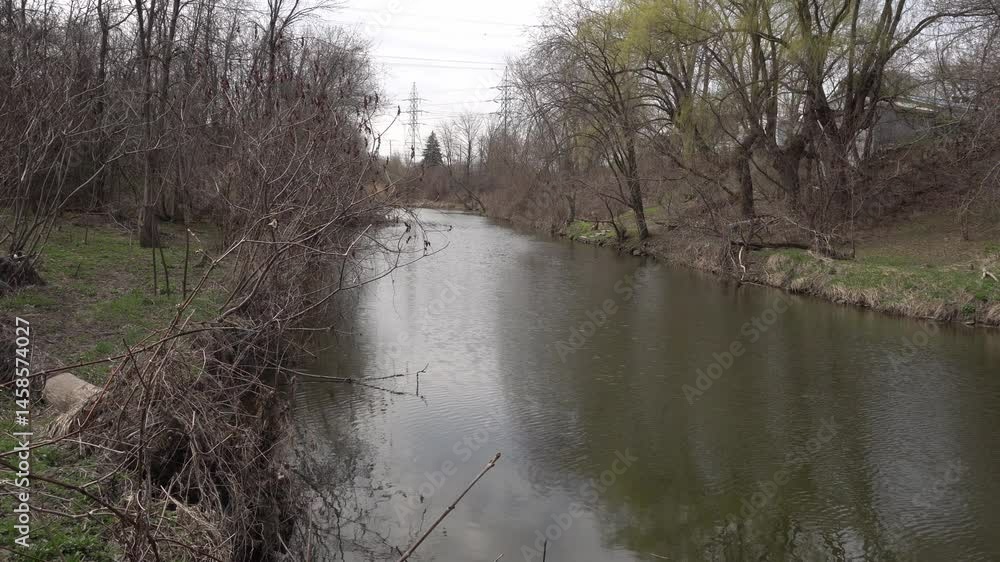 Poster a small river flowing for eternity with leafless trees at the beginning of spring. in the distance, 