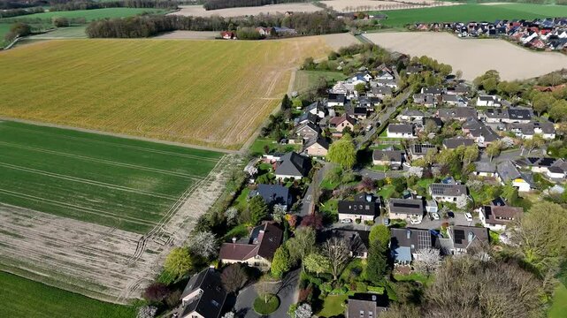 Single family houses with solar panel bordering to rural colored farm fields in America. Sunny day in spring season. Aerial top down flyer shot. Quiet suburb housing area.