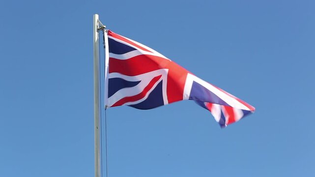 Flag of UK on a flagpole in front of blue sky