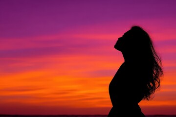 Fototapeta premium Silhouette of a woman against a vibrant sunset sky expressing tranquility and introspection captured in stunning gradient hues creating a serene and contemplative atmosphere