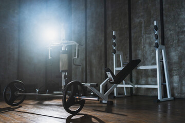 Empty gym workout area health club. Dark interior of gym with fitness equipment barbell. Weights of fitness sports for exercise. Machines tools for exercising. Training for strength building wellness
