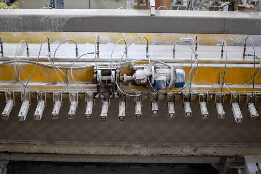 Industrial production of aerated concrete blocks, AAC blocks (Autoclaved aerated concrete), Fly ash or Grey Cement Fly Ash Bricks. The machine cuts the large workpiece into parts with steel strings.